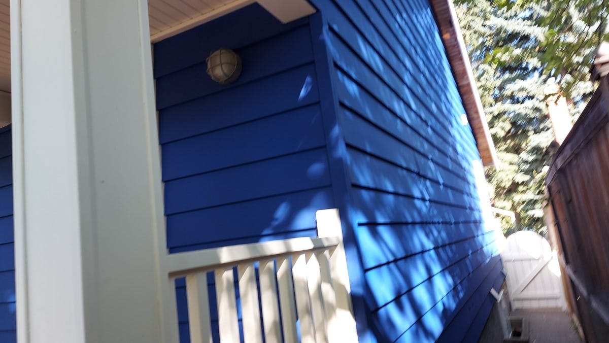 exterior siding of a house  after being painted with a navy blue, left side of the house looking from the stareet, the actual colour was light brown, in Calgary