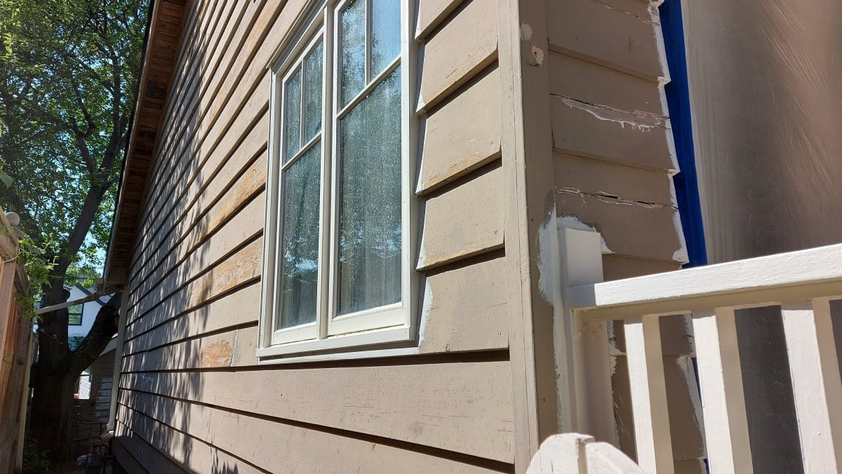 exterior siding of a house  being prepared for exterior painting ,right side of the house looking from the stareet, the actual colour is light brown, in Calgary