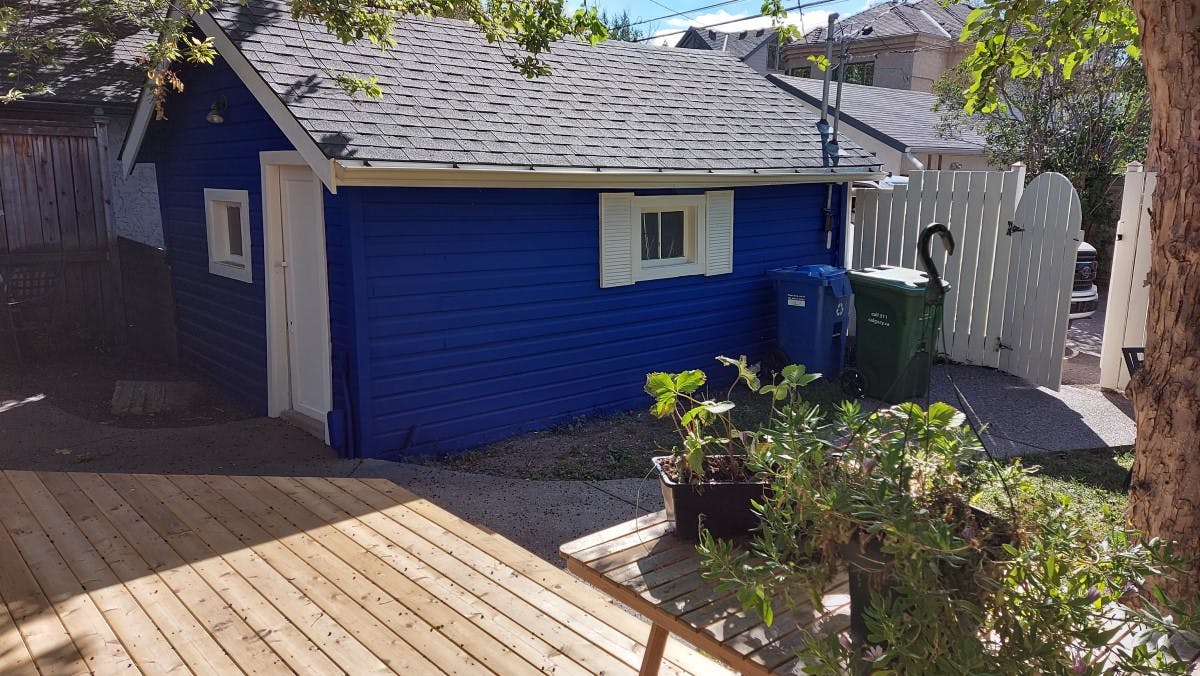 exterior siding of a house  after being painted with a navy blue, garage at the back, the actual colour was light brown, in Calgary