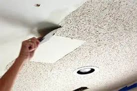 A Calgary Popcorn ceiling being removed by hand with a putty knife. All you can see from the person doin t is his or her arm